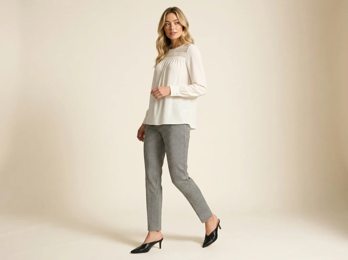 Blonde woman walking in profile wearing a Vince Camuto ivory long-sleeve blouse, houndstooth skinny pants, and black kitten-heel mules[cite: 33].