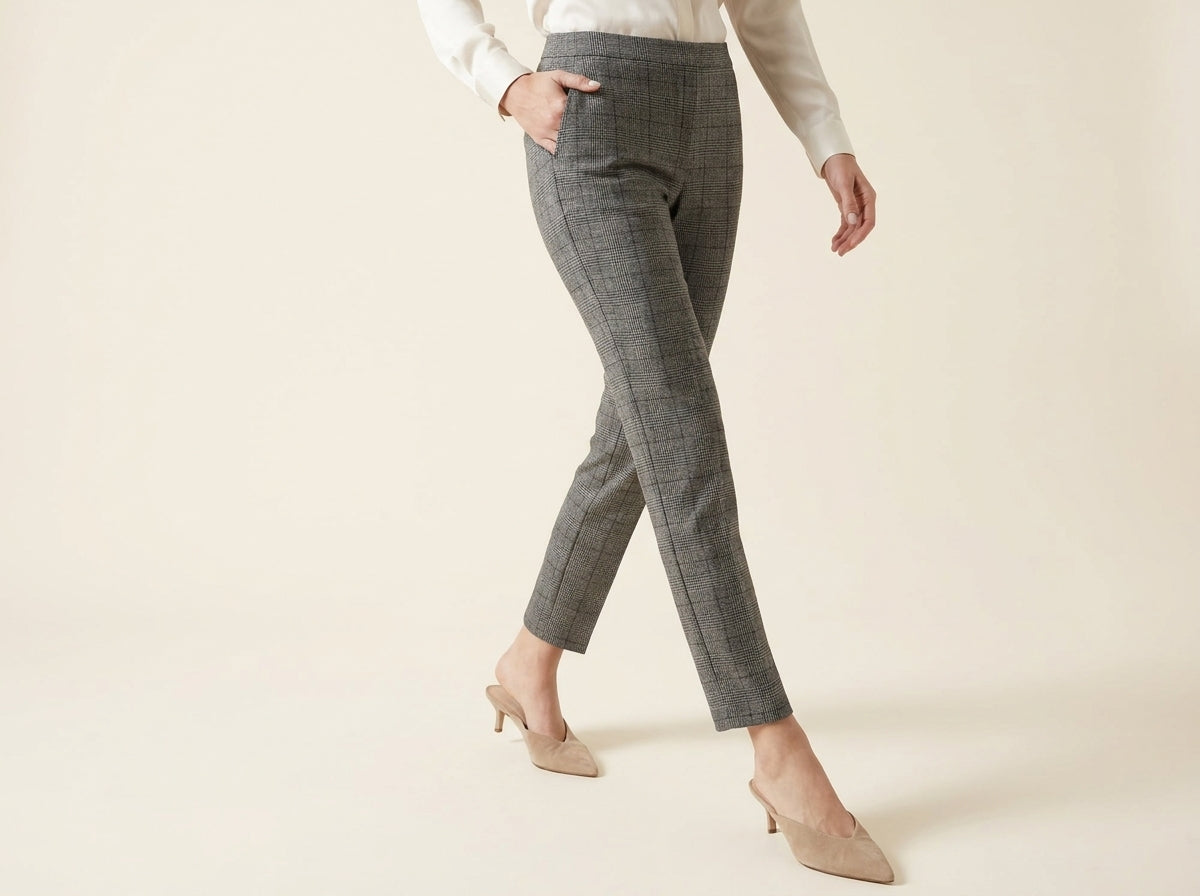 Cropped view of a woman wearing grey Glen plaid slim-leg ankle trousers with side pockets and pointed-toe kitten heel mules.