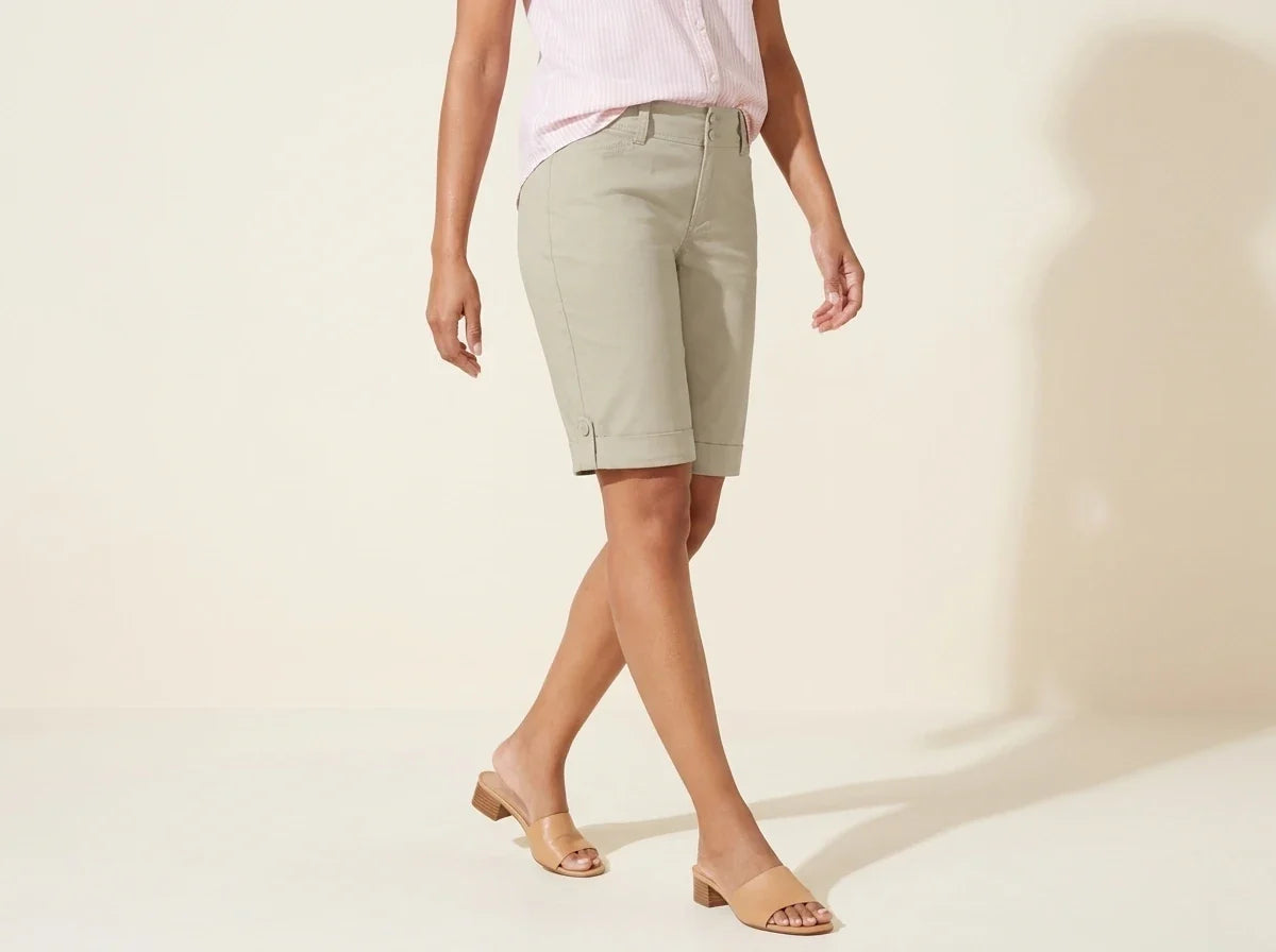 Cropped view of a woman wearing Charter Club sage green Bermuda shorts with side-slit button details, a pink striped shirt, and tan mule sandals[cite: 32].
