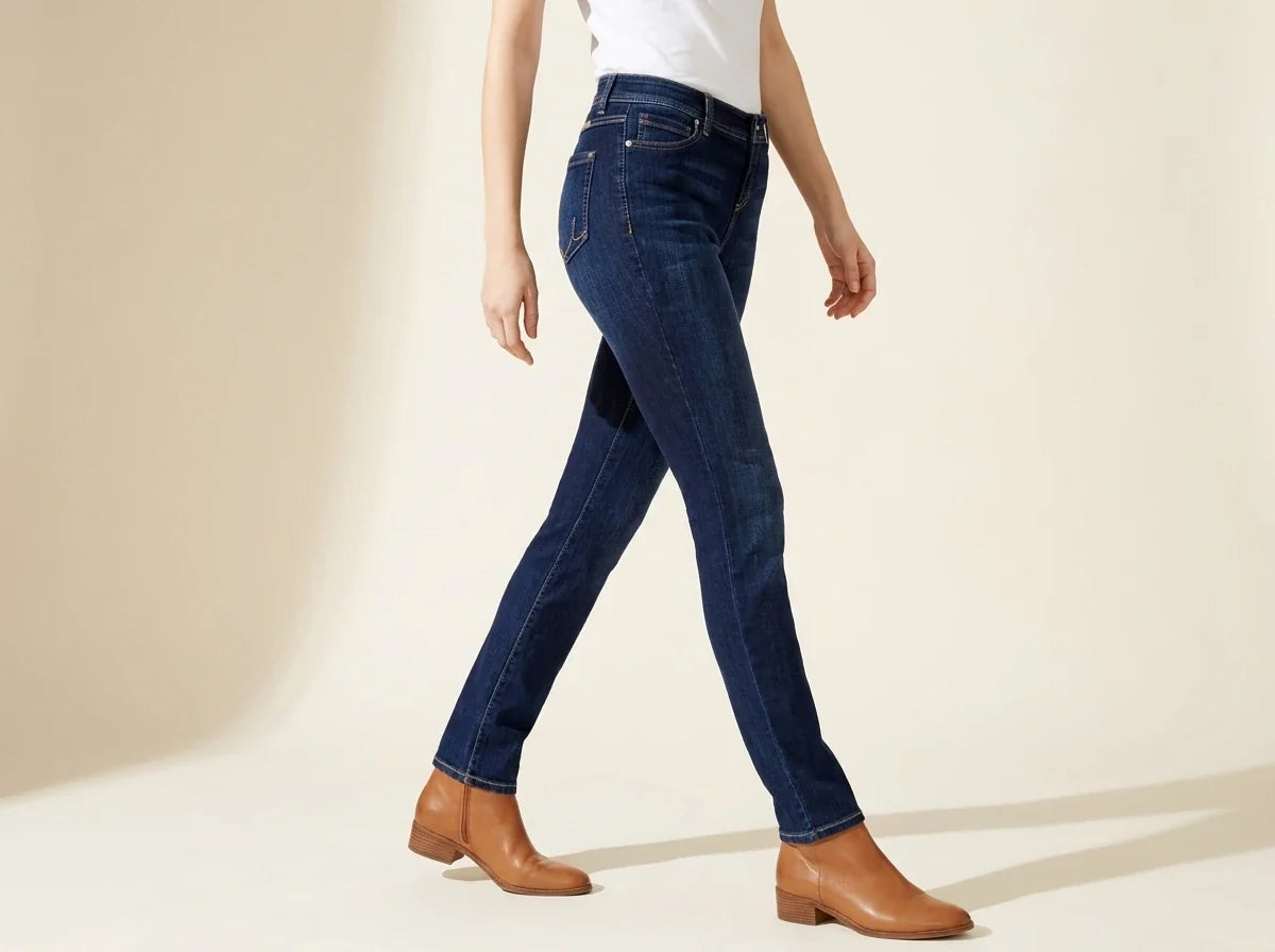 Cropped view of a woman walking in dark-wash slim straight jeans paired with tan leather ankle boots.