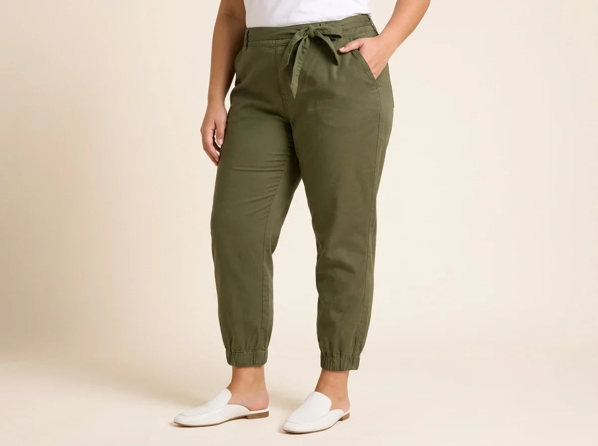 Cropped view of a woman wearing olive green tie-waist jogger pants with elastic cuffs, paired with flat white leather mules.