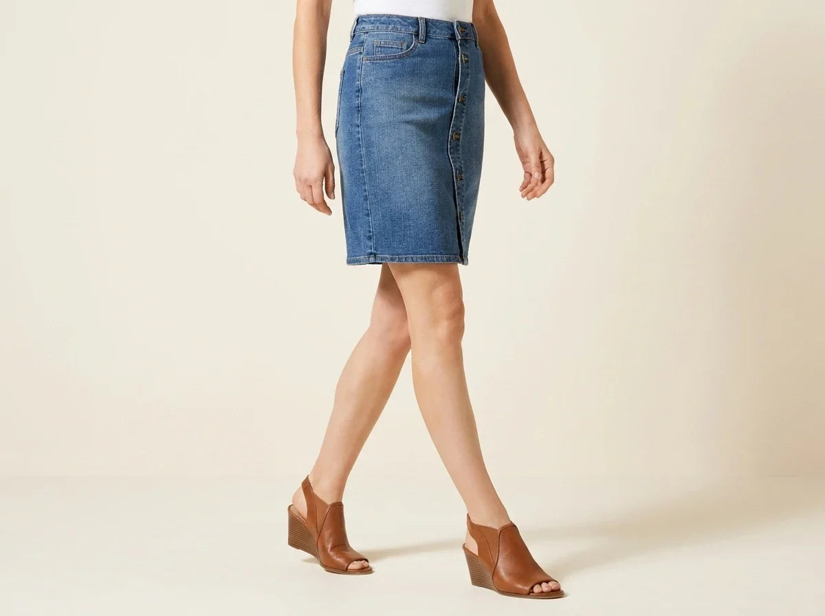 Cropped view of a woman wearing a petite button-front medium wash denim mini skirt with brown open-toe wedge sandals.