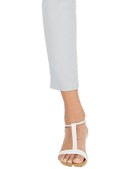 White sandal worn with light gray pants on a white background