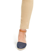 Denim wedge sandal worn with beige pants on a white background