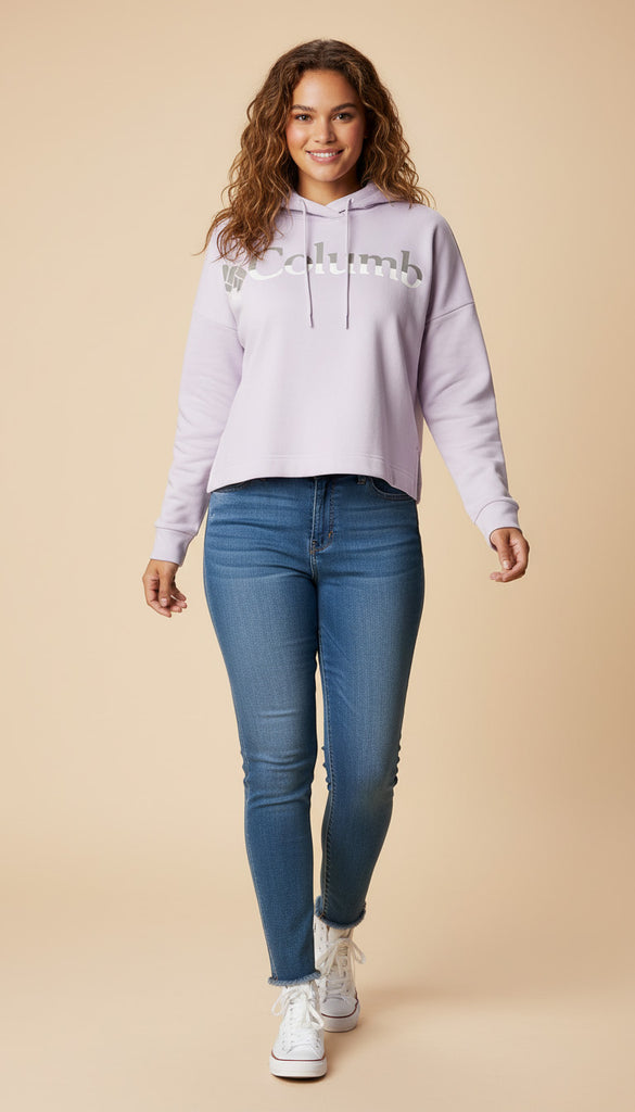 Woman wearing a light purple hoodie with text and blue jeans on a beige background