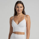 A woman wearing a white, solid-patterned bralette with a V-neckline and adjustable straps.