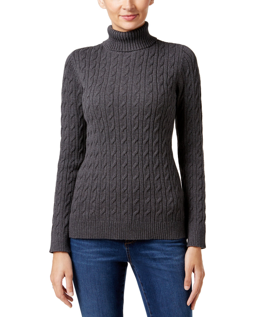 Person wearing a gray cable knit turtleneck sweater on a white background