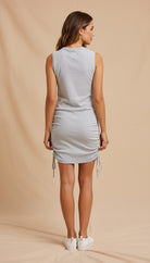 Woman wearing a light gray dress against a beige background