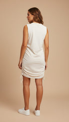 Woman wearing a white sleeveless dress on a beige background