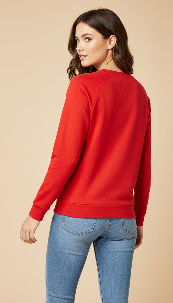 Woman wearing a red sweatshirt and blue jeans on a beige background