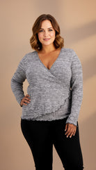 Woman wearing a gray sweater with a plain background