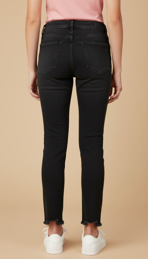 Person wearing black jeans and white sneakers on a beige background