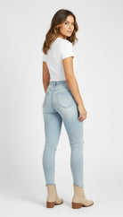 Woman wearing light blue jeans and a white top on a white background