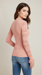 Woman wearing a pink sweater and blue jeans on a beige background