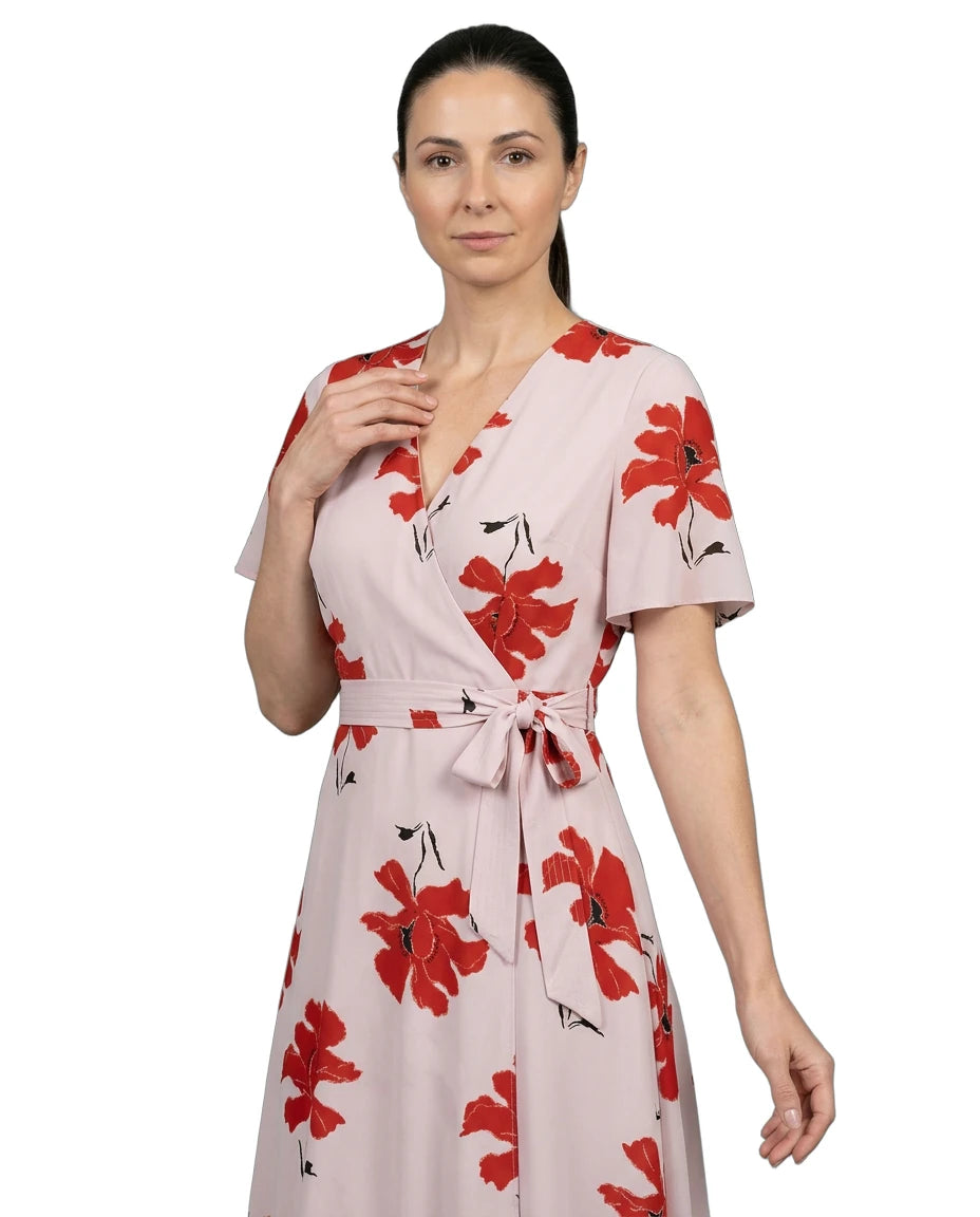 Woman wearing a pink dress with red floral patterns on a white background
