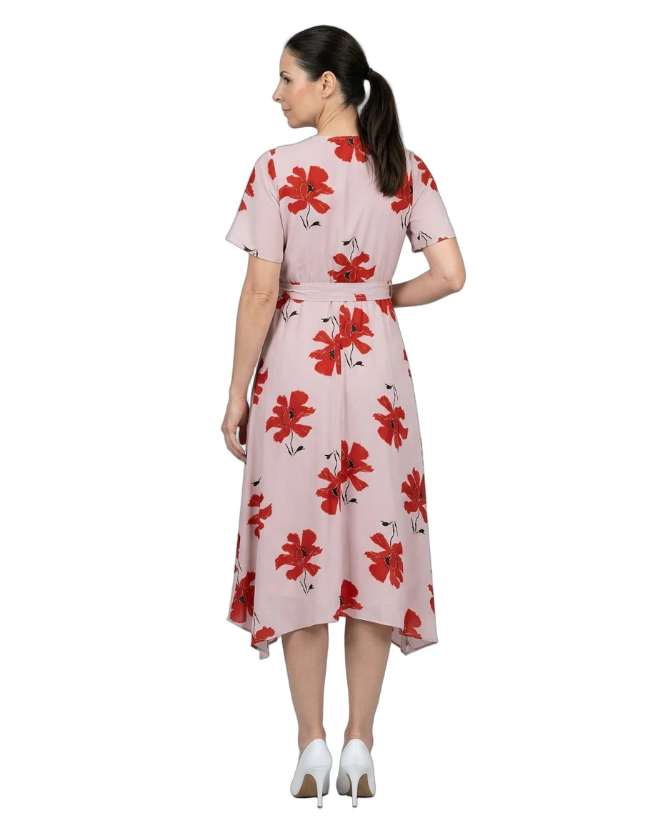 Woman wearing a pink dress with red floral pattern on a white background