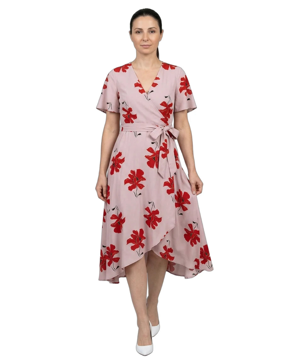 Woman wearing a pink dress with red floral pattern on a white background