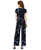 Woman wearing a black jumpsuit with blue butterfly pattern on a white background