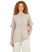 Woman wearing a beige patterned shirt on a white background