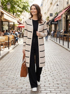 Woman in a striped coat walking down a street with cafes in the background