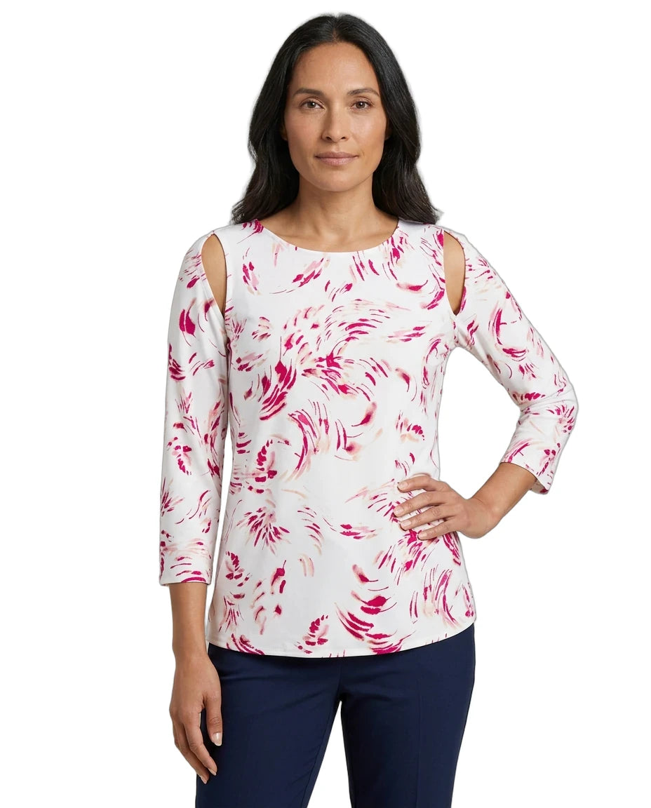 A woman modeling a white three-quarter sleeve top with pink abstract swirl patterns and cold-shoulder cutouts, paired with navy pants, against a plain white background.