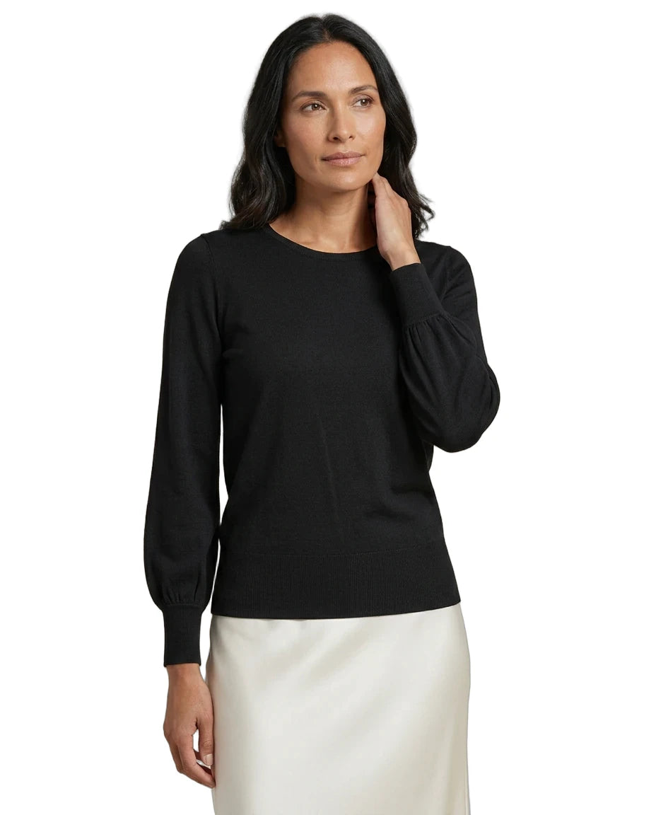 A woman modeling a black long-sleeve knit top with balloon sleeves, paired with a white skirt, against a plain white background.