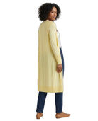 Woman wearing a long light yellow cardigan over a white top and dark pants on a white background