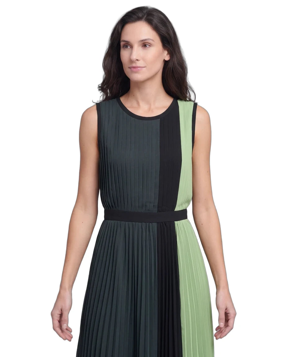 A woman modeling a sleeveless pleated dress with vertical color-blocked panels in dark charcoal gray, black, and light sage green, featuring a matching waistband.