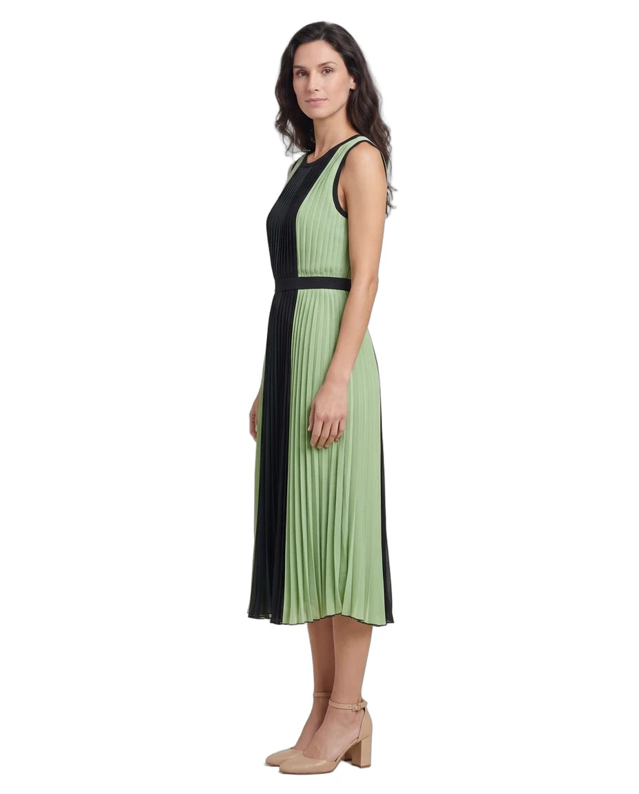 A woman modeling a sleeveless pleated midi dress with a color-blocked design in sage green and black, paired with beige block-heel sandals, against a plain white background.