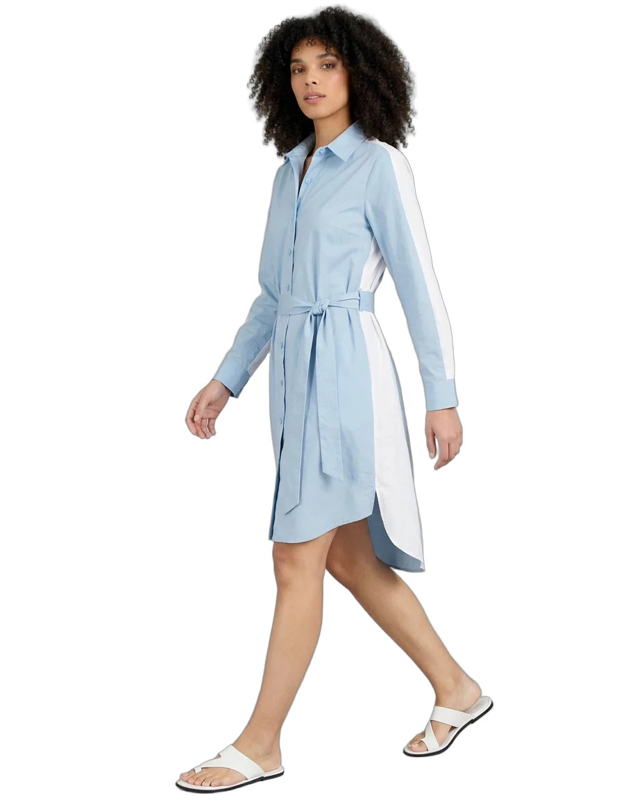 A woman modeling a light blue collared shirt dress with white side panels and a matching waist tie, paired with white slide sandals, on a solid white background.
