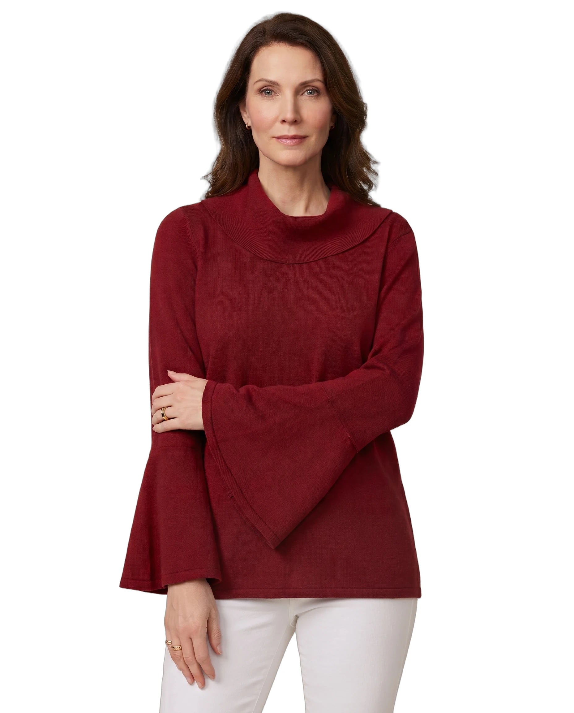 A woman modeling a long-sleeve knit top with a high folded mock neck and wide flared bell sleeves, in a deep burgundy red, paired with white pants against a plain white background.