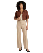 A woman modeling a brown short-sleeve cropped button-up shirt, beige wide-leg trousers, a cream top, and black heels against a plain white background.