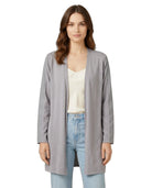Woman wearing a gray cardigan over a white top and blue jeans on a white background