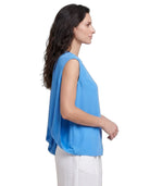 Woman wearing a blue sleeveless top and white pants on a white background
