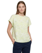 A woman modeling a pale yellow-green short-sleeve knit top with a subtle horizontal textured pattern, paired with navy blue pants, against a plain white background.