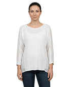 Woman wearing a white long-sleeve top and dark jeans on a white background