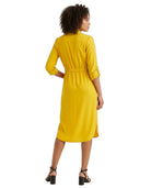 A woman wearing a bright yellow midi shirt dress, shown from the back. The dress features three-quarter sleeves with button details at the cuffs, a high mock neck, and a gathered elastic waist.