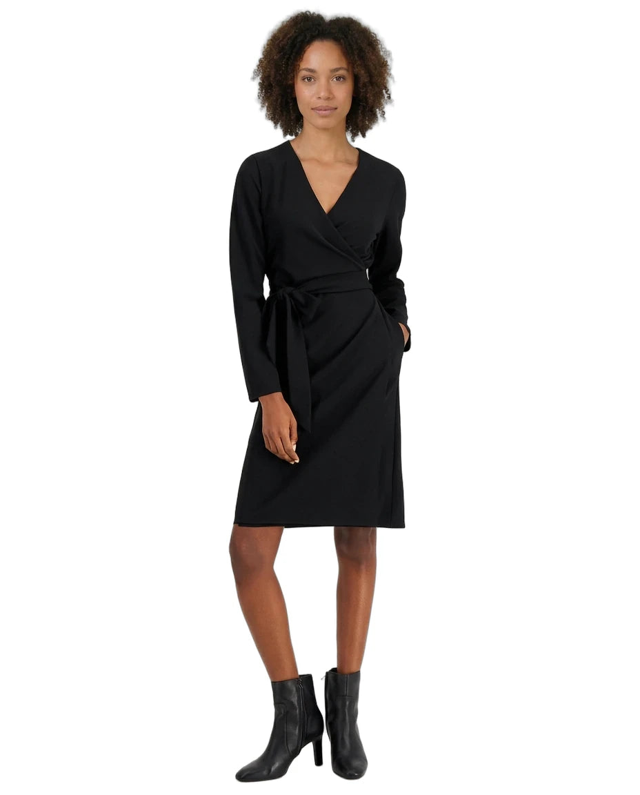 A woman modeling a black long-sleeve wrap dress with a matching waist tie, paired with black ankle boots, against a plain white background.