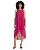 A woman modeling a sleeveless high-low midi dress in a vibrant magenta pink, paired with black strappy high-heeled sandals, against a plain white background.