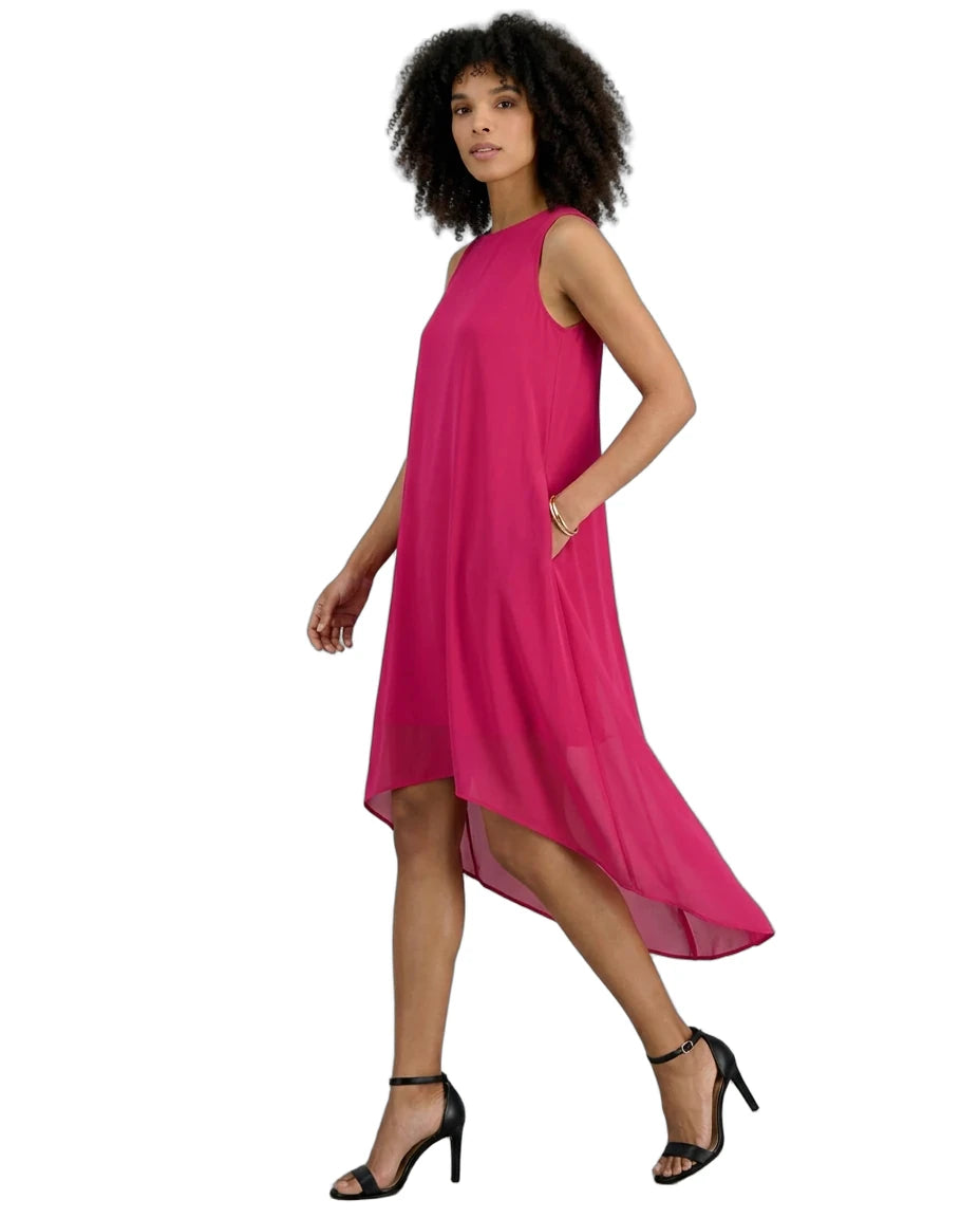 A woman modeling a sleeveless, high-low magenta dress with side pockets, paired with black strappy high-heeled sandals, against a plain white background.