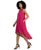 A woman modeling a sleeveless, high-low magenta dress with side pockets, paired with black strappy high-heeled sandals, against a plain white background.