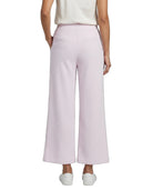 A model shown from the back wearing light pink wide-leg cropped pants, a cream top, and white sneakers against a plain white background.