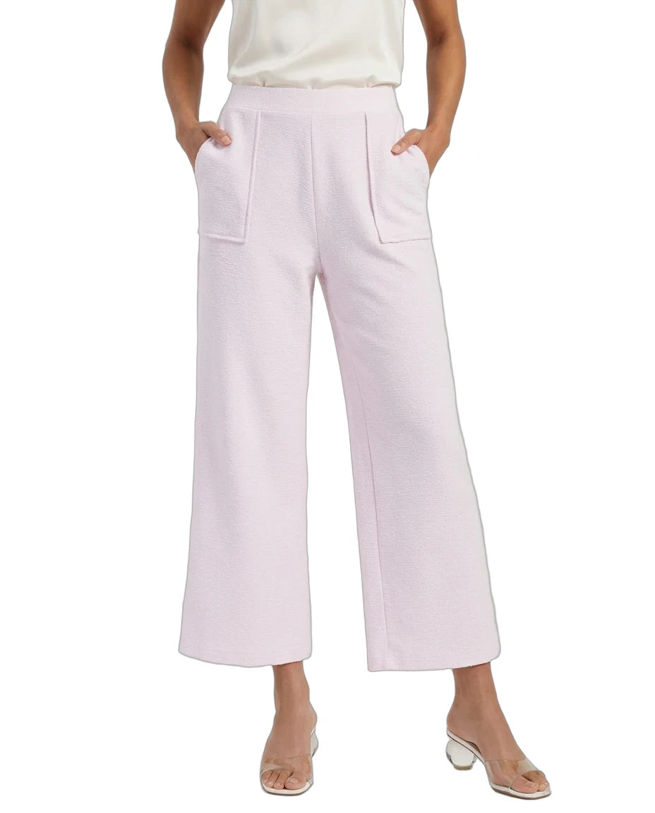 A model wearing light pink wide-leg cropped pants with front patch pockets, paired with a cream satin top and clear heeled sandals, shown against a plain white background.