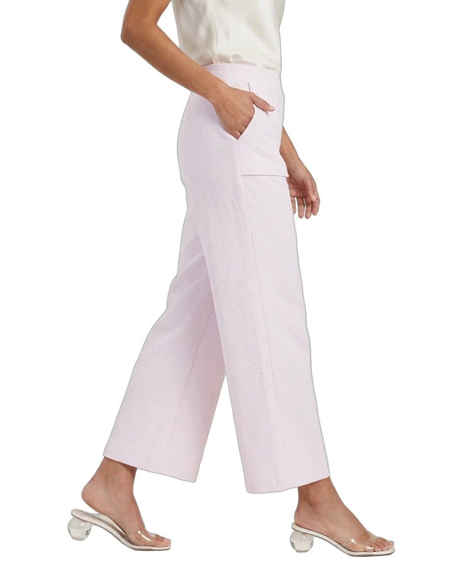 A model wearing light pink cropped wide-leg pants with side pockets, paired with a white top and clear block-heel mule sandals, shown against a plain white background.