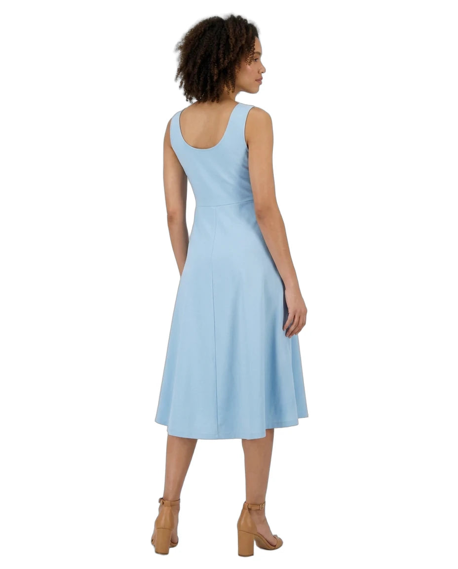 A woman shown from the back wearing a sleeveless light blue midi dress and tan ankle-strap heels against a plain white background.