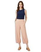 A woman modeling a sleeveless navy blue top and light peach wide-leg cropped pants with elastic cuffs, paired with tan heeled sandals, against a plain white background.