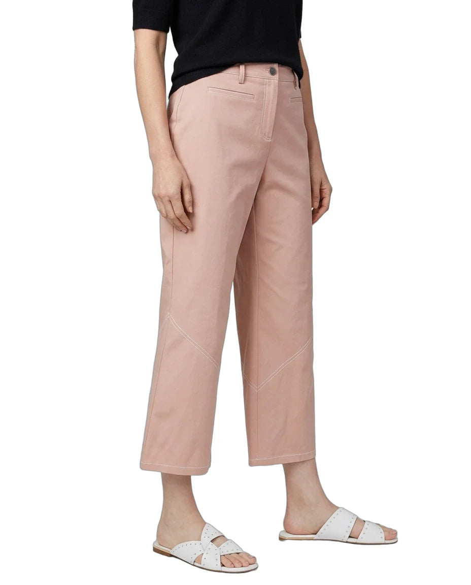 A model wearing dusty pink cropped pants, a black t-shirt, and white slide sandals, shown from the waist down against a plain white background.