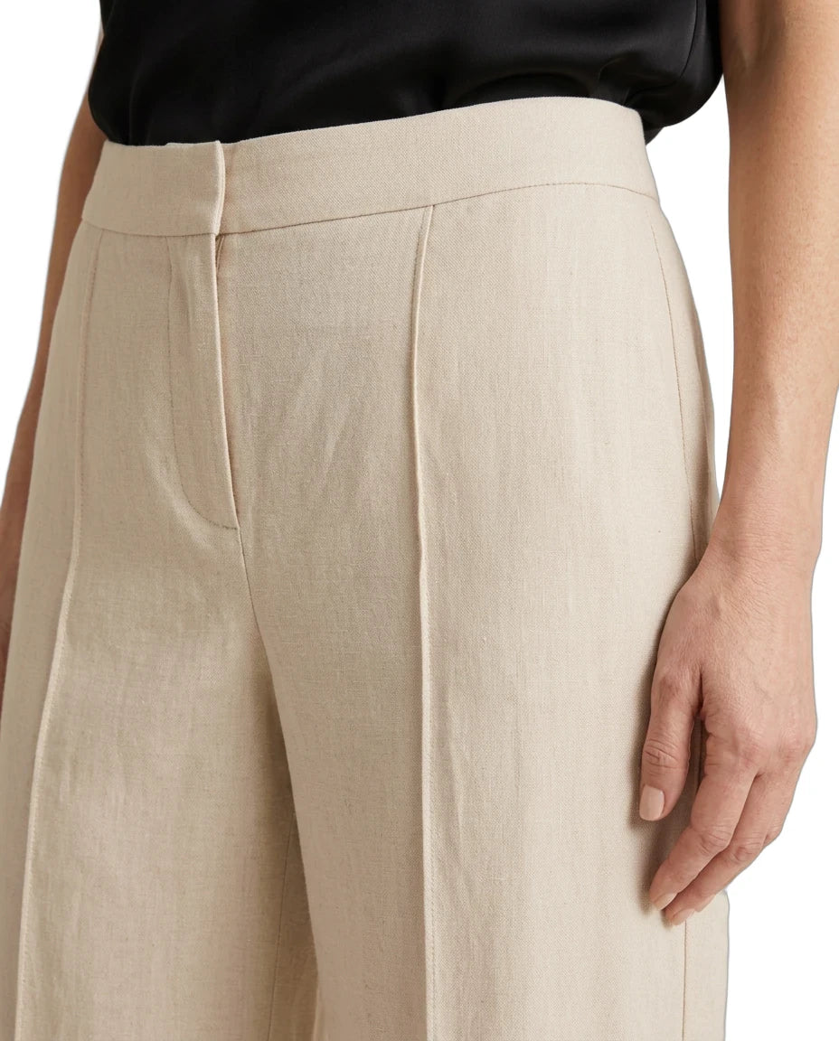 Close-up of a person wearing high-waisted, wide-leg trousers in a light beige linen-like fabric, paired with a black top against a plain white background.