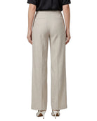 A model shown from the back wearing high-waisted, wide-leg trousers in a light beige linen-like fabric, paired with a black top and white heels, on a solid white background.