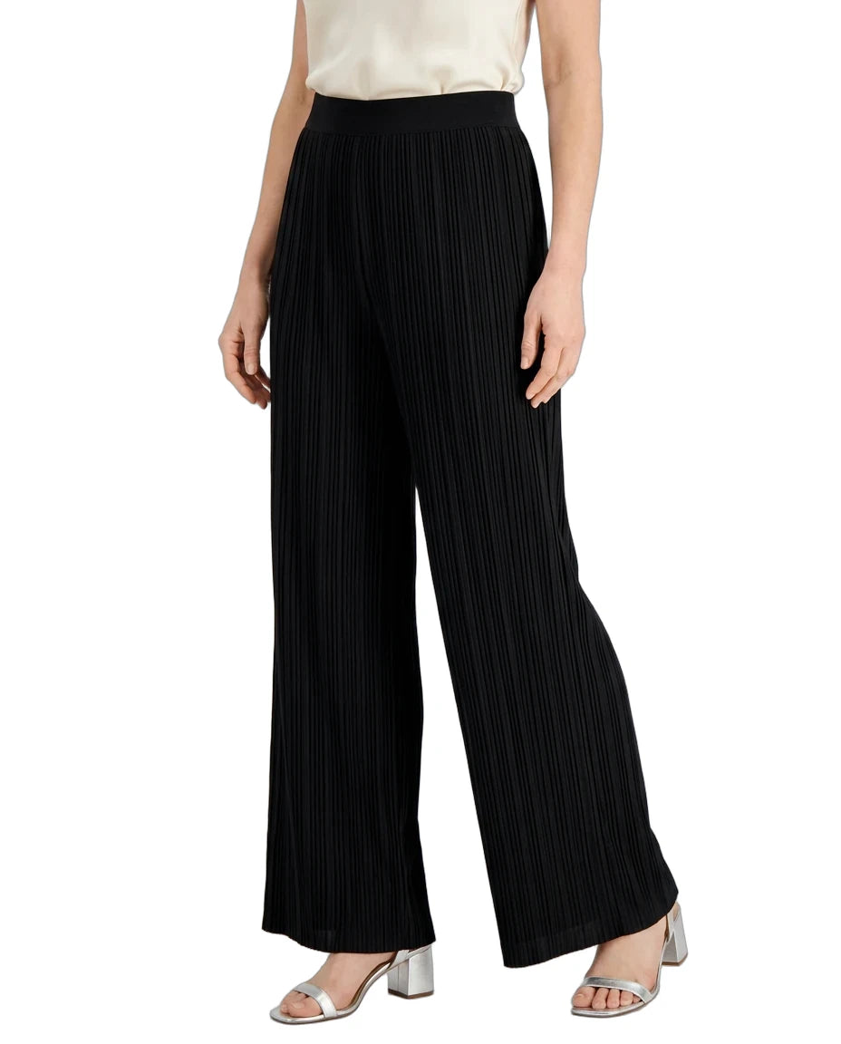 Black wide-leg pleated trousers worn by a model, paired with a cream top and metallic silver block-heel sandals, shown against a plain white background.